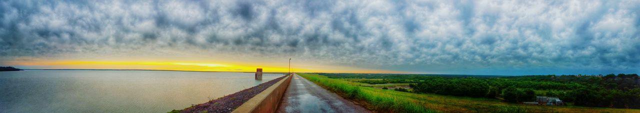 Road passing through landscape against cloudy sky