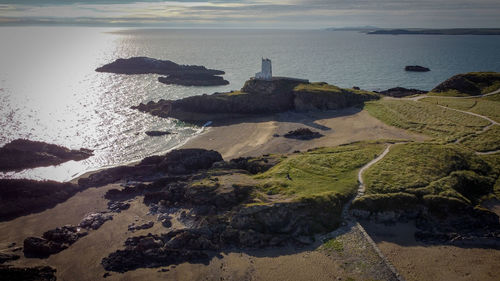 High angle view of lighthouse on rocks and beach against sky