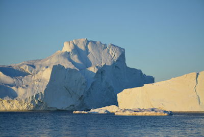 Scenic view of sea against clear sky with beautiful icebergs in the midnight sun ilulissat greenland