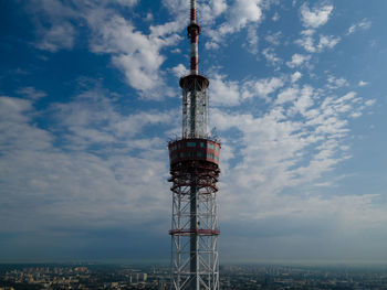 Low angle view of communications tower in city against sky