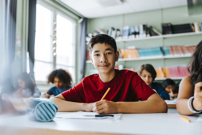 Portrait of boy sitting in classroom with classmates at elementary school