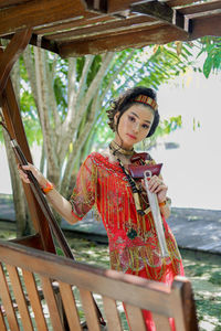 Portrait of smiling young woman standing by railing
