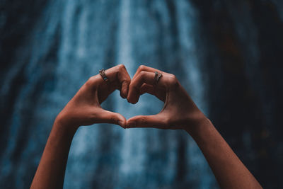 Close-up of woman hand holding heart shape against blurred background