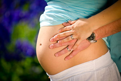 Midsection of woman with arms raised standing outdoors