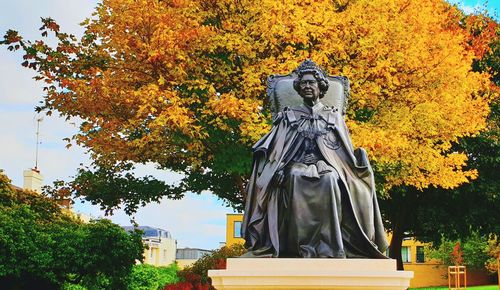 Low angle view of statue against trees during autumn