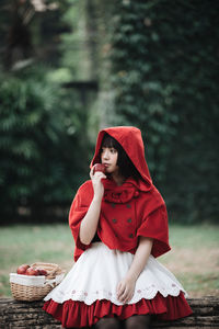 Young woman with red umbrella standing against plants