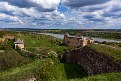 Castle on landscape against cloudy sky