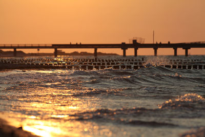 Bridge over sea against sky during sunset