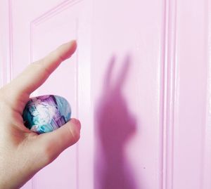 Cropped hand holding easter egg by door