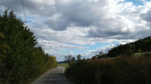 Road amidst trees against sky