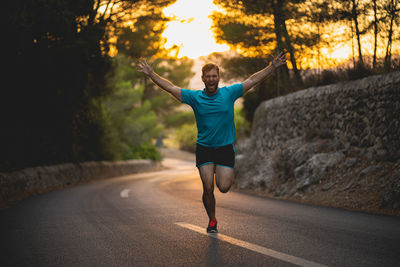 Young man jogging on road amidst trees