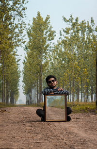 Portrait of boy sitting on seat against trees