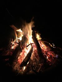 Close-up of firewood burning on field at night