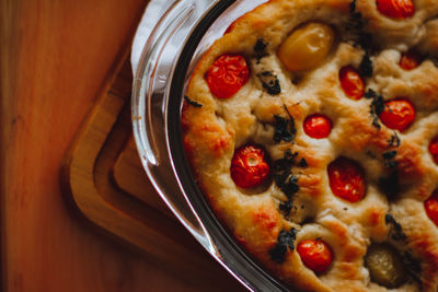 Close-up of food on table. homemade italian focaccia, with tomato, pink pepper and olive oil.