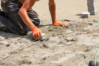 A worker pulls a nylon thread to lay paving slabs on a bright sunny summer day. copy space.