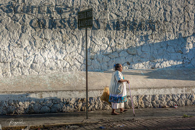 Full length of woman standing against wall