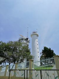 Low angle view of lighthouse by building against sky