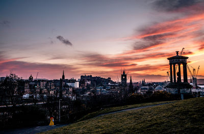 Illuminated buildings against sky during sunset