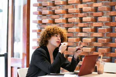 Portrait of smiling young woman using digital tablet while sitting on table