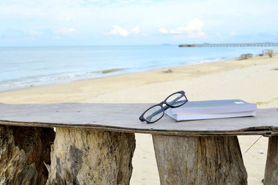 Close-up of deck chairs on beach against sky