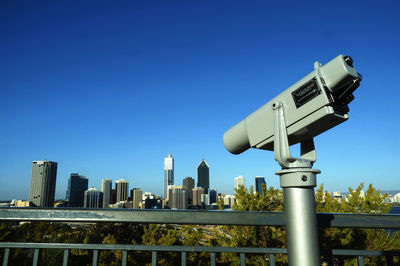 Coin operated binoculars at kings park against clear blue sky over city