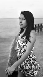 Thoughtful woman standing by sea against sky