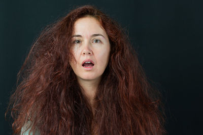 Portrait of distraught woman against black background staring at camera