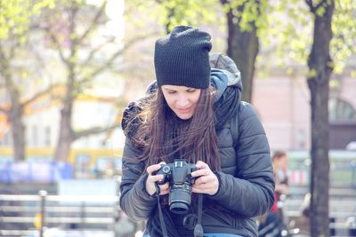 Portrait of smiling young woman photographing through camera