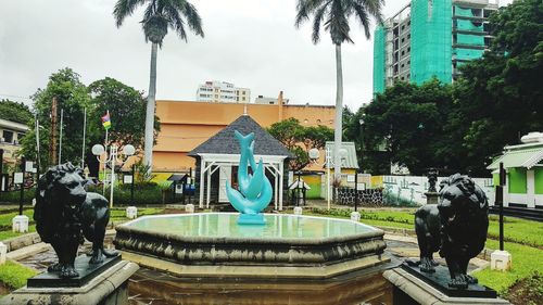 Statue in park by city against sky