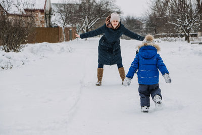 Outdoor family activities for happy winter holidays. happy mother and two sons playing snowballs on