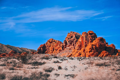 Rock formations on landscape against blue sky