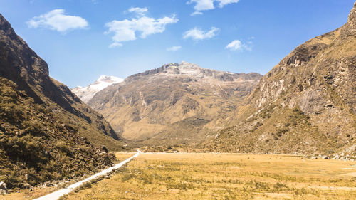 Scenic view of road leading towards mountains against sky