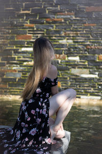 Midsection of woman sitting against wall