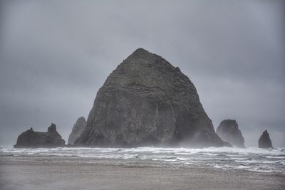 Rock formation on beach against sky