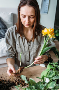 Young woman is transplanting houseplant. spring fertilizer for home flowers