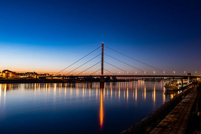 Illuminated bridge over river against clear sky at night at blue hour with reflexion