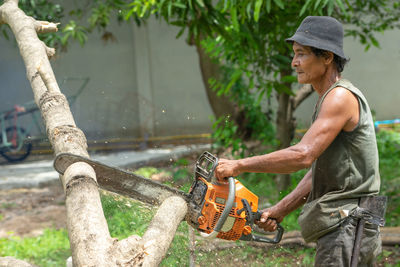 Side view of man working on tree