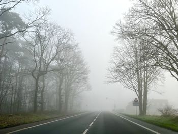 Road amidst bare trees against sky