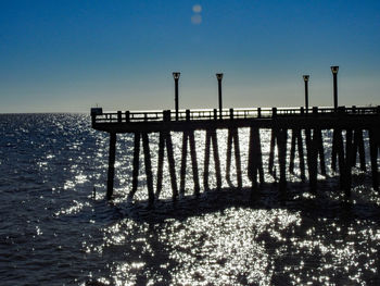 Pier over sea against clear blue sky