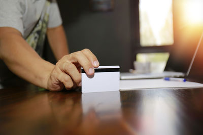 Midsection of man using mobile phone on table