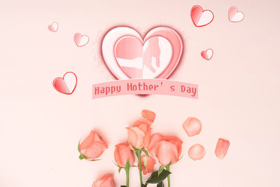 Close-up of heart shape with pink flower on white background