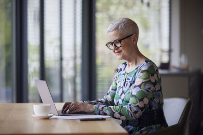 Senior woman using laptop at table at home