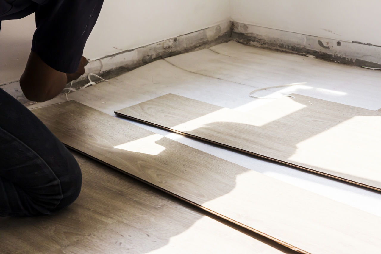 LOW SECTION VIEW OF PERSON STANDING ON HARDWOOD FLOOR