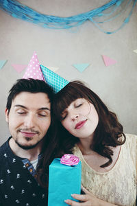 Close-up of couple with gift box against wall during birthday