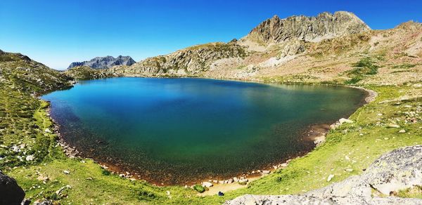 Scenic view of lake and mountains against clear blue sky