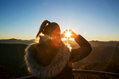 Woman standing on road against sky during sunset