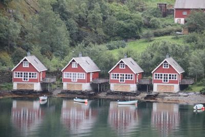 Houses by lake and buildings against trees