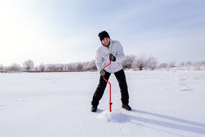 Full length of man standing with pole on snow against sky