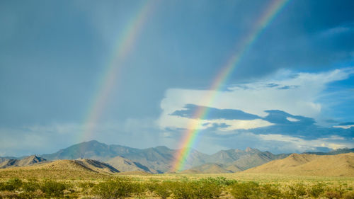 Scenic view of rainbow over mountains against sky