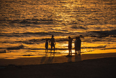 Silhouette people on beach during sunset